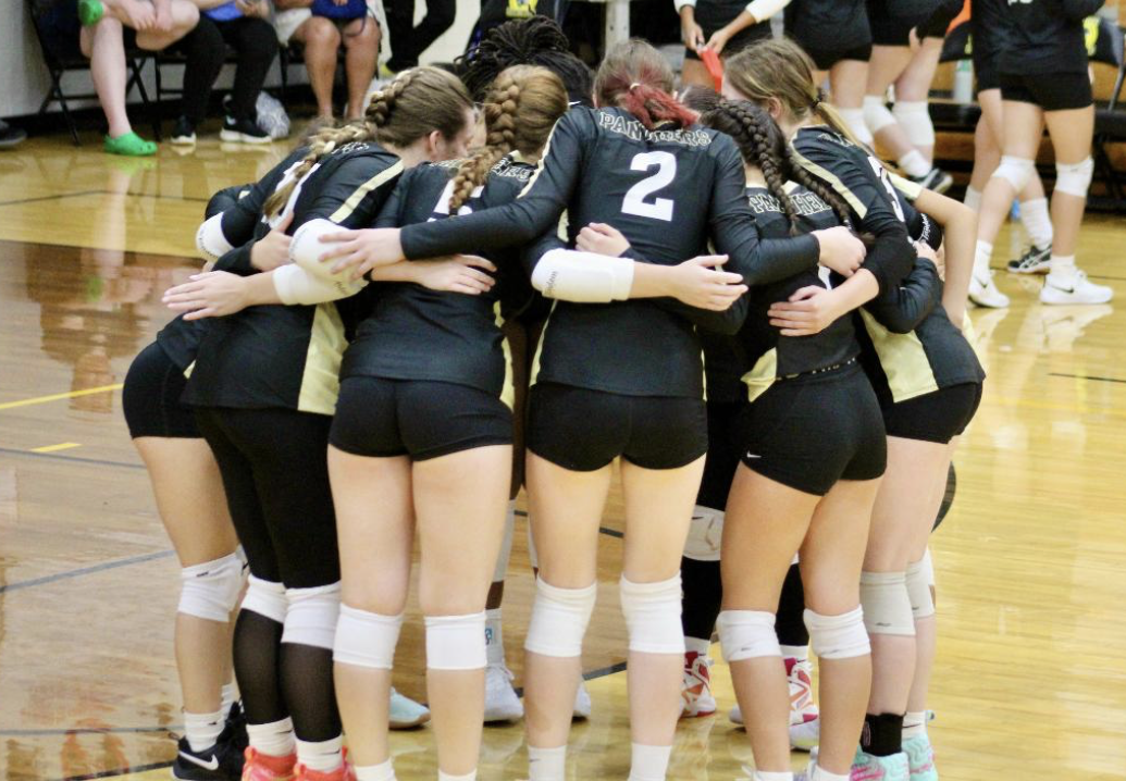 The volleyball team huddles up,  communicating the strategy for the next play.