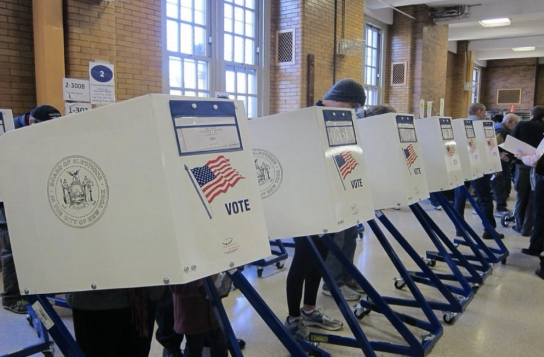 Individuals cast their ballots at a voting booth.