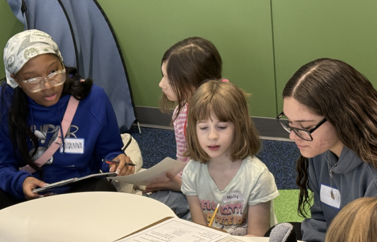 High schoolers Aubree Newsome and Rihanna Moore socializing with Mrs. Elomar's second graders on January 27 in Wadsworth's library. The high schoolers were in charge of assisting the second graders in writing a story about their monsters.