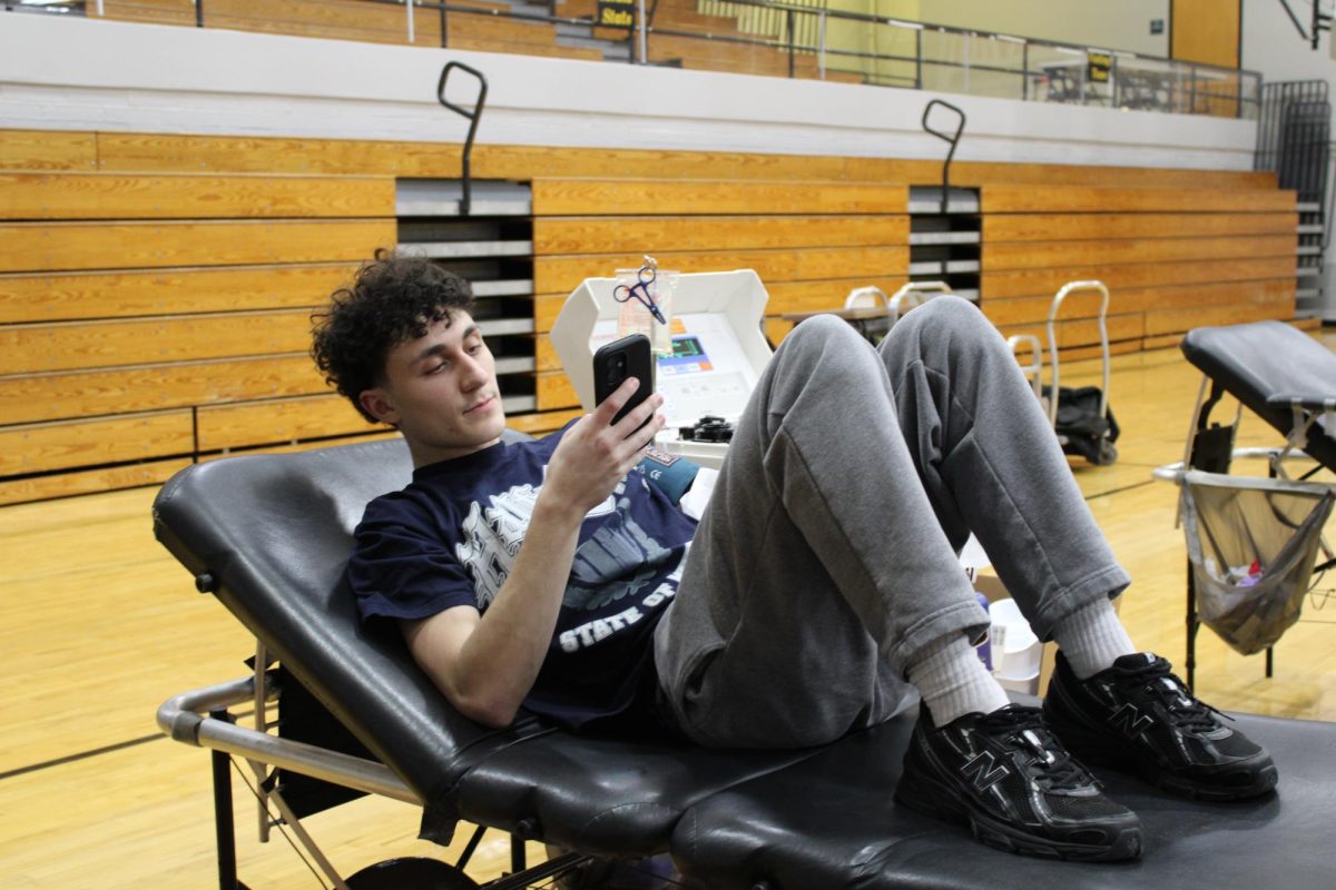 Junior Rocco Miraglia uses his phone during the annual blood drive in the Griffith main gym on February 6. The registration and consent was online and required students to access the platform during school hours.